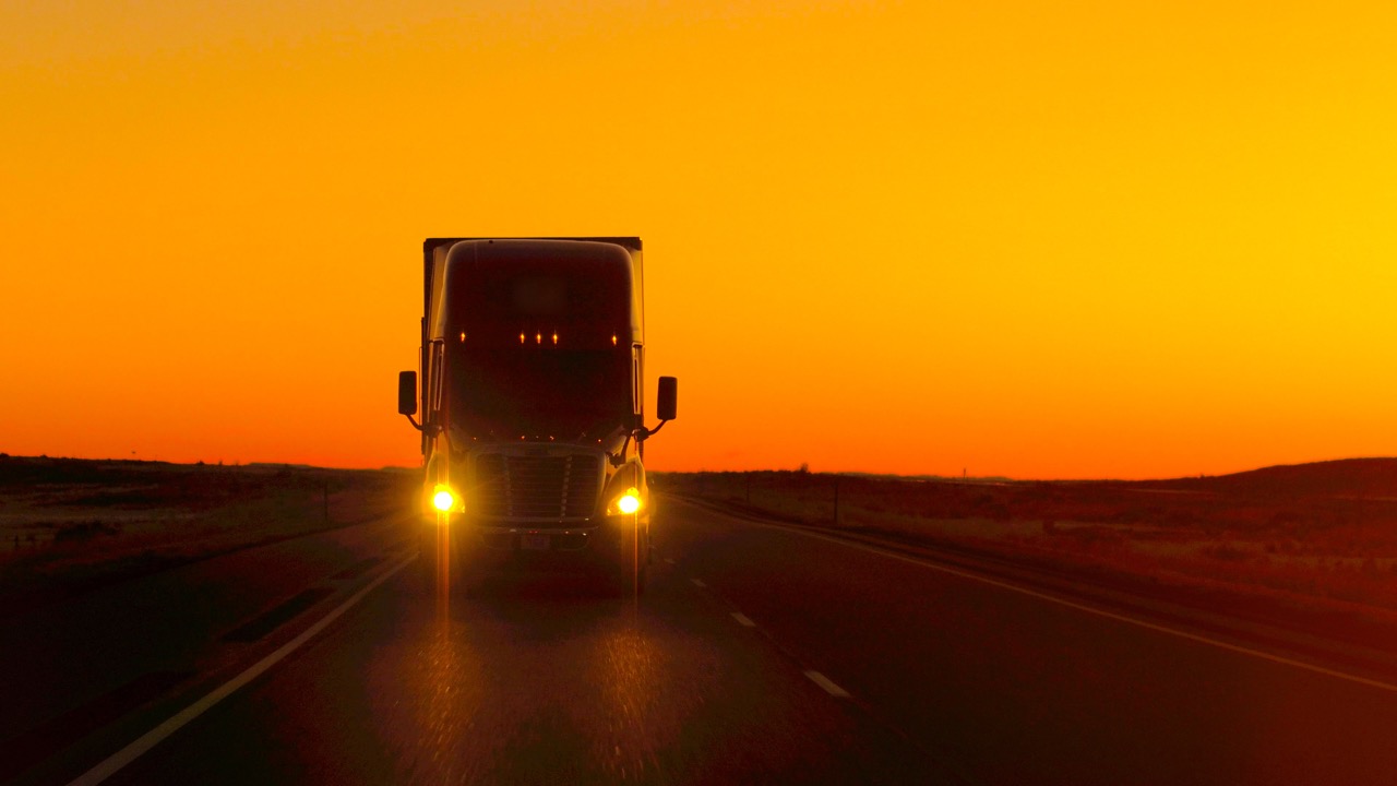 longhaul truck driving on highway at sunset